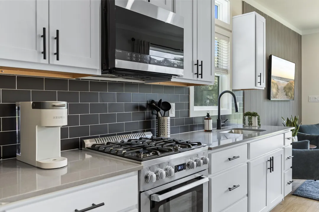 Cottage kitchen with white cabinets, a gas range and a tile backsplash