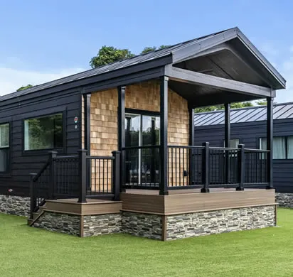 Cottage with a covered porch and stone skirting on a green lawn