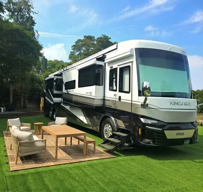 RV site with a motorhome, deck and patio furniture on the lawn