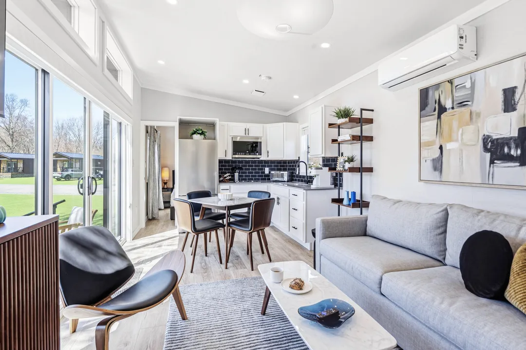 Inside a cottage: an open living room with a gray sofa, dining table and kitchen