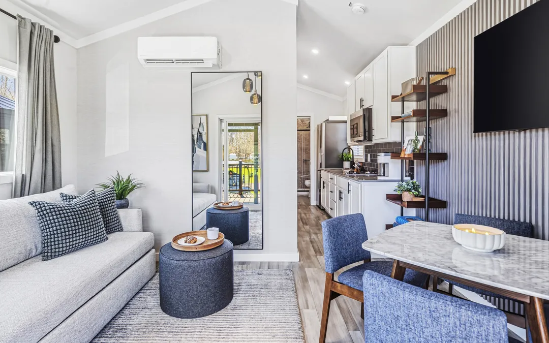 Inside a move-in-ready cottage: a sofa and ottoman, the kitchen and a dining table