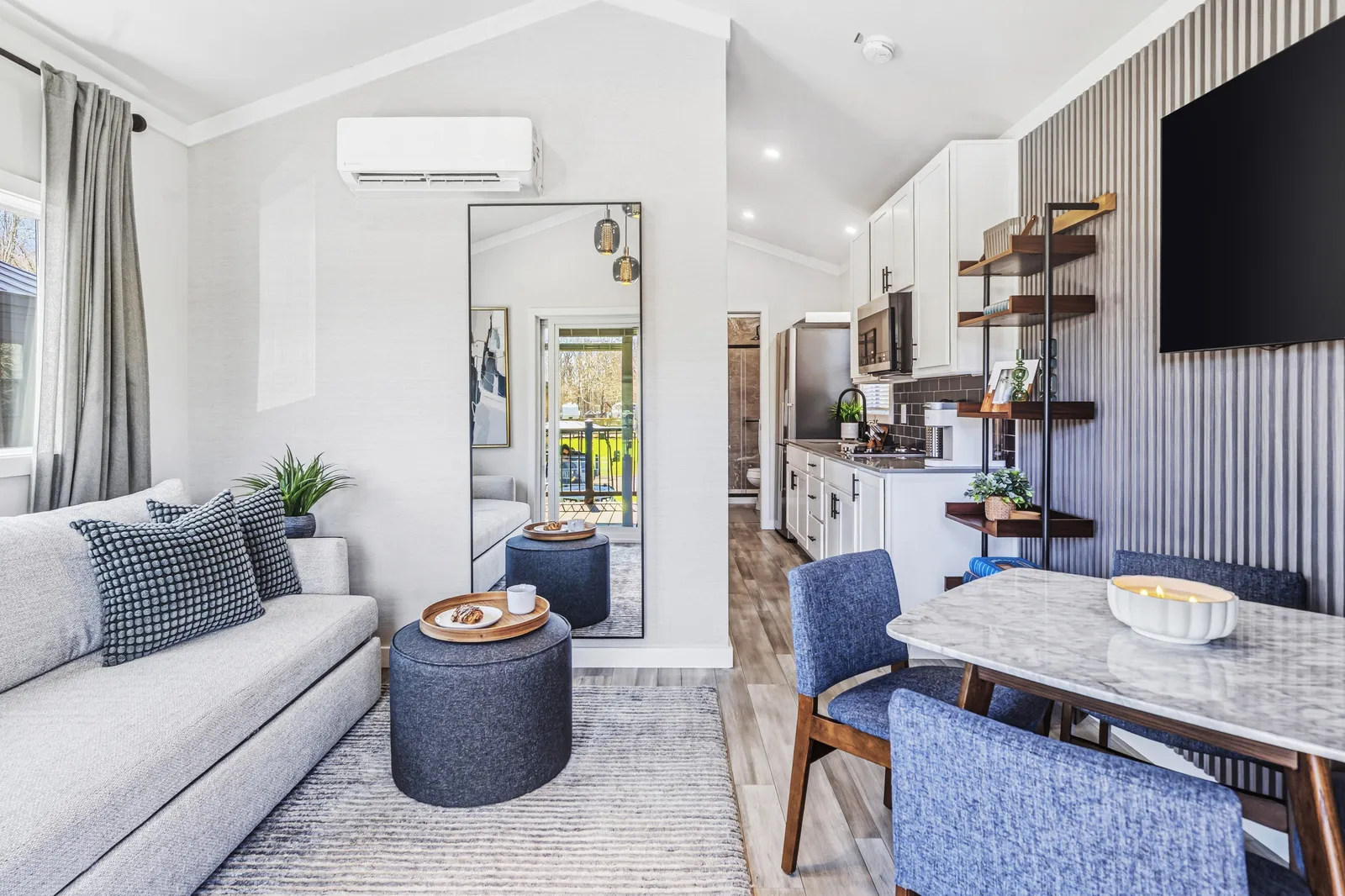 Inside a move-in-ready cottage: a sofa and ottoman, the kitchen and a dining table