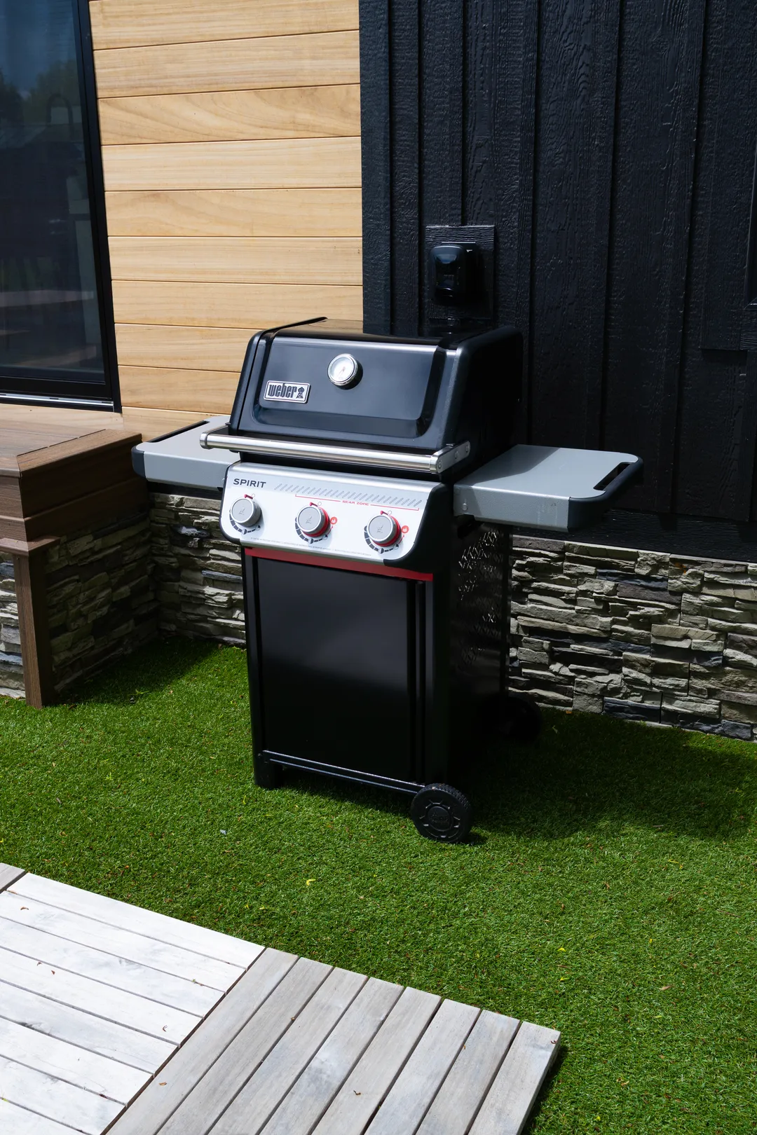 A Weber gas grill on the patio beside a cottage