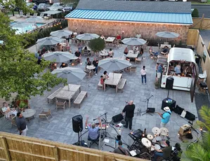 Live band playing on the patio at Miss May's with guests at tables under umbrellas