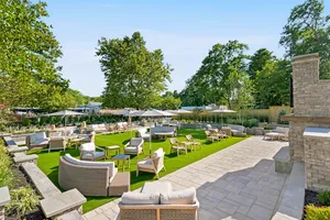 Outdoor Living Room patio with lounge seating, lawn and a stone fireplace