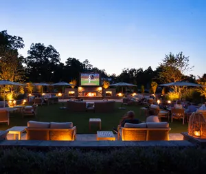 Outdoor movie screen on the patio at dusk with lounge seating