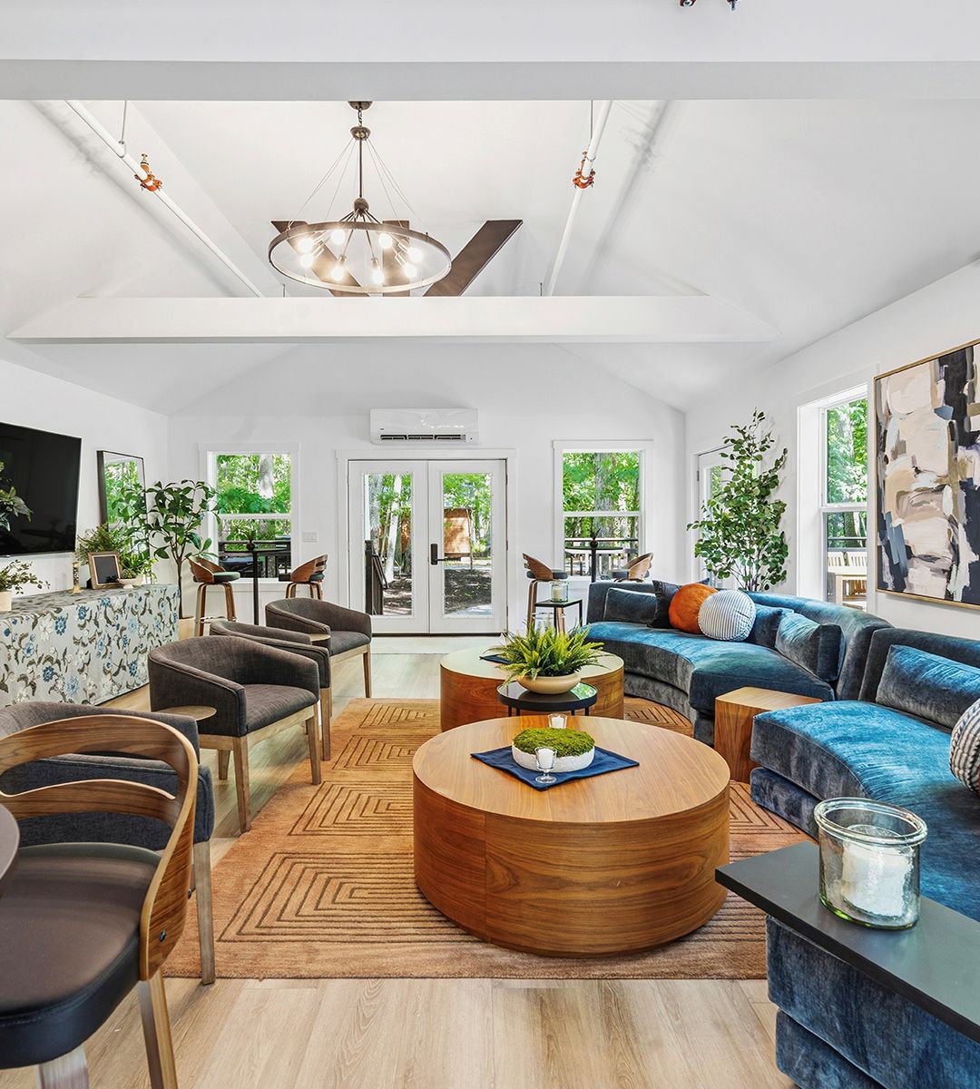 The Beechwood Club lounge at North Fork Resort with blue velvet sofas, a round wood table and a vaulted ceiling