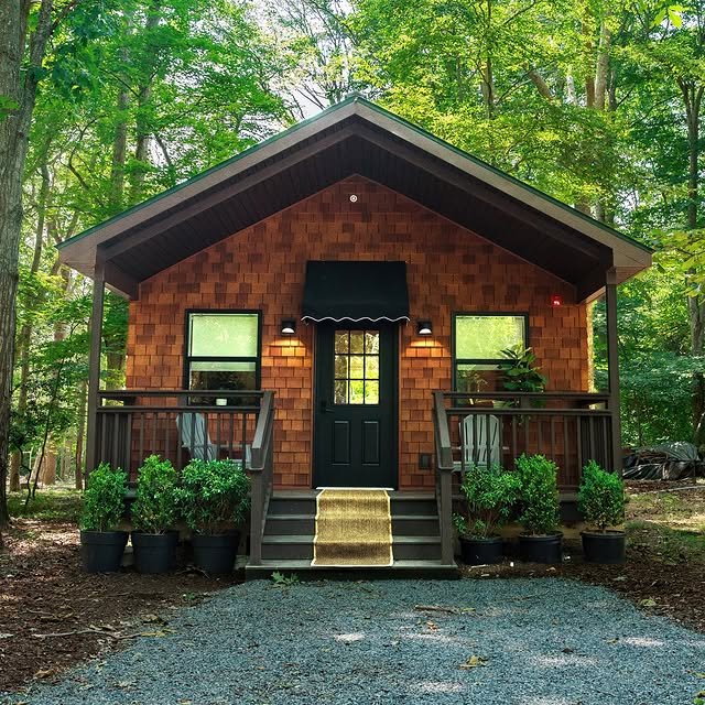 A cedar-shingle Beechwood Cottage at North Fork Resort with a striped awning and a porch in the trees