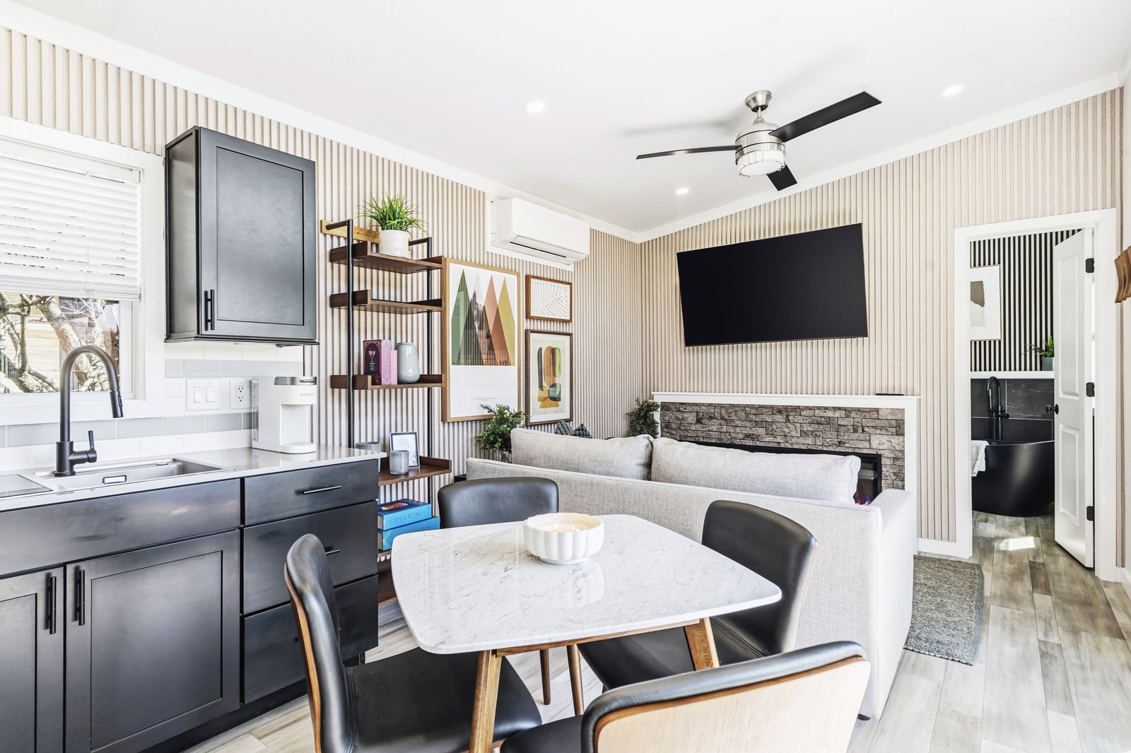 Inside a North Fork Resort cottage: kitchen, dining table and living room with a stone fireplace