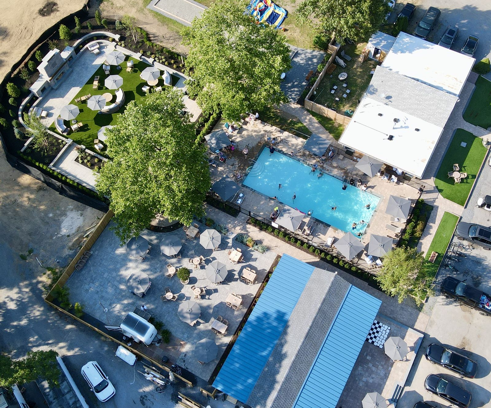 Drone photo from summer 2026 of The Living Room, the pool, Miss May's and the open field next to them