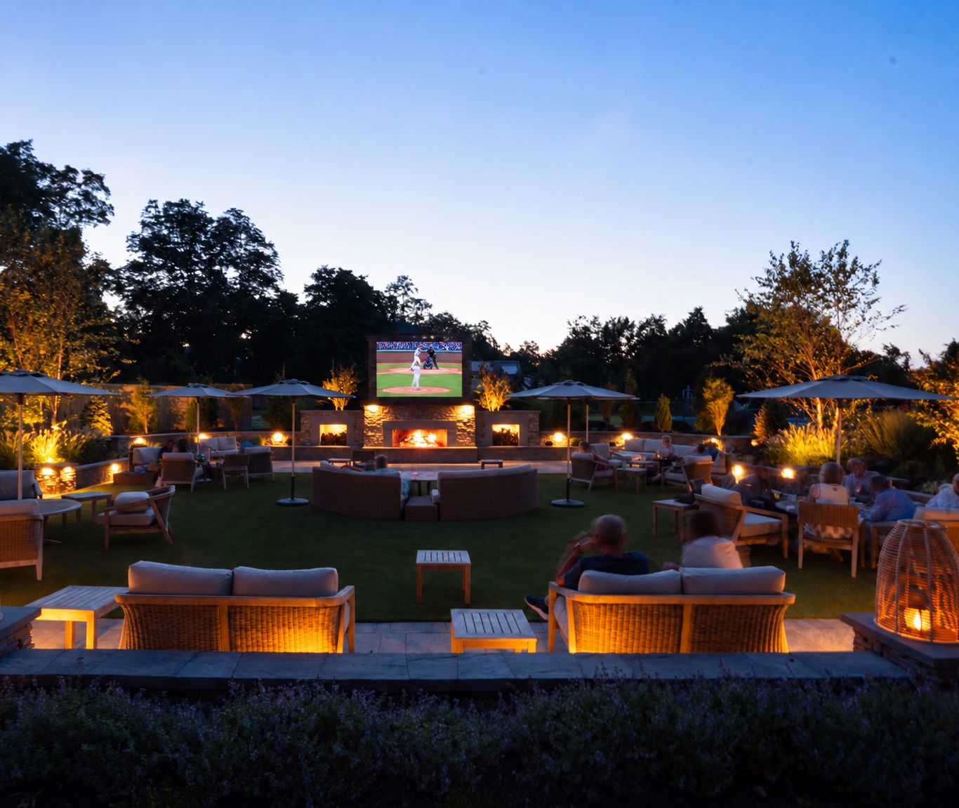 The Living Room at dusk with the stone fireplace lit and guests on the lounge sofas